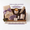 The image is a gift set featuring various items related to yoga and relaxation, including a yoga mat, a candle, a towel, a soap bar, and a sachet.