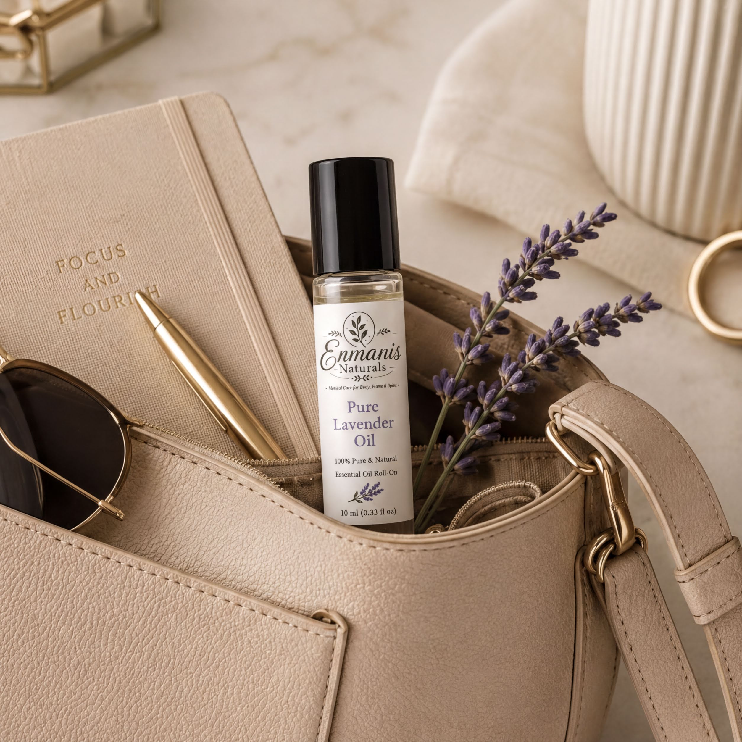 A beige leather handbag with a bottle of pure lavender essential oil, a gold pen, and a pair of sunglasses placed in it.