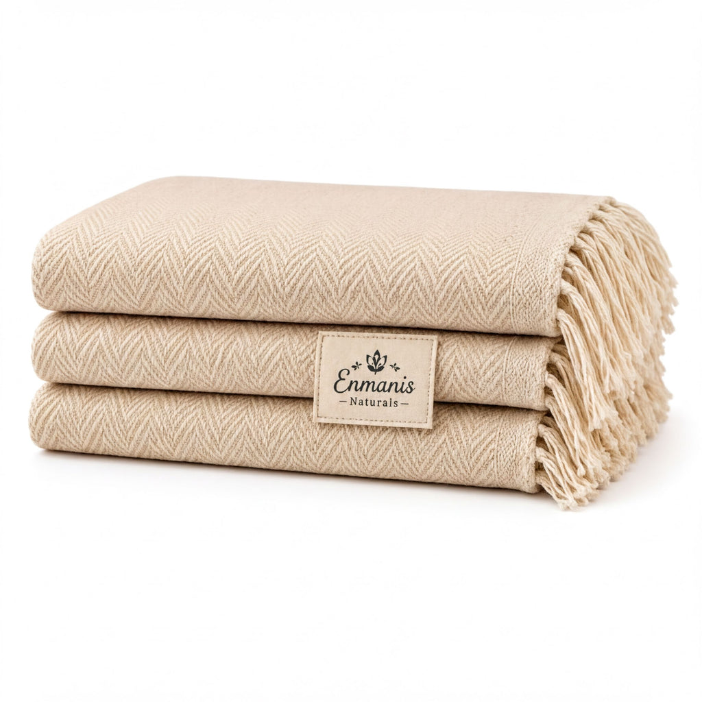A stack of three beige towels with fringe, each labeled "Enmanis Naturals".