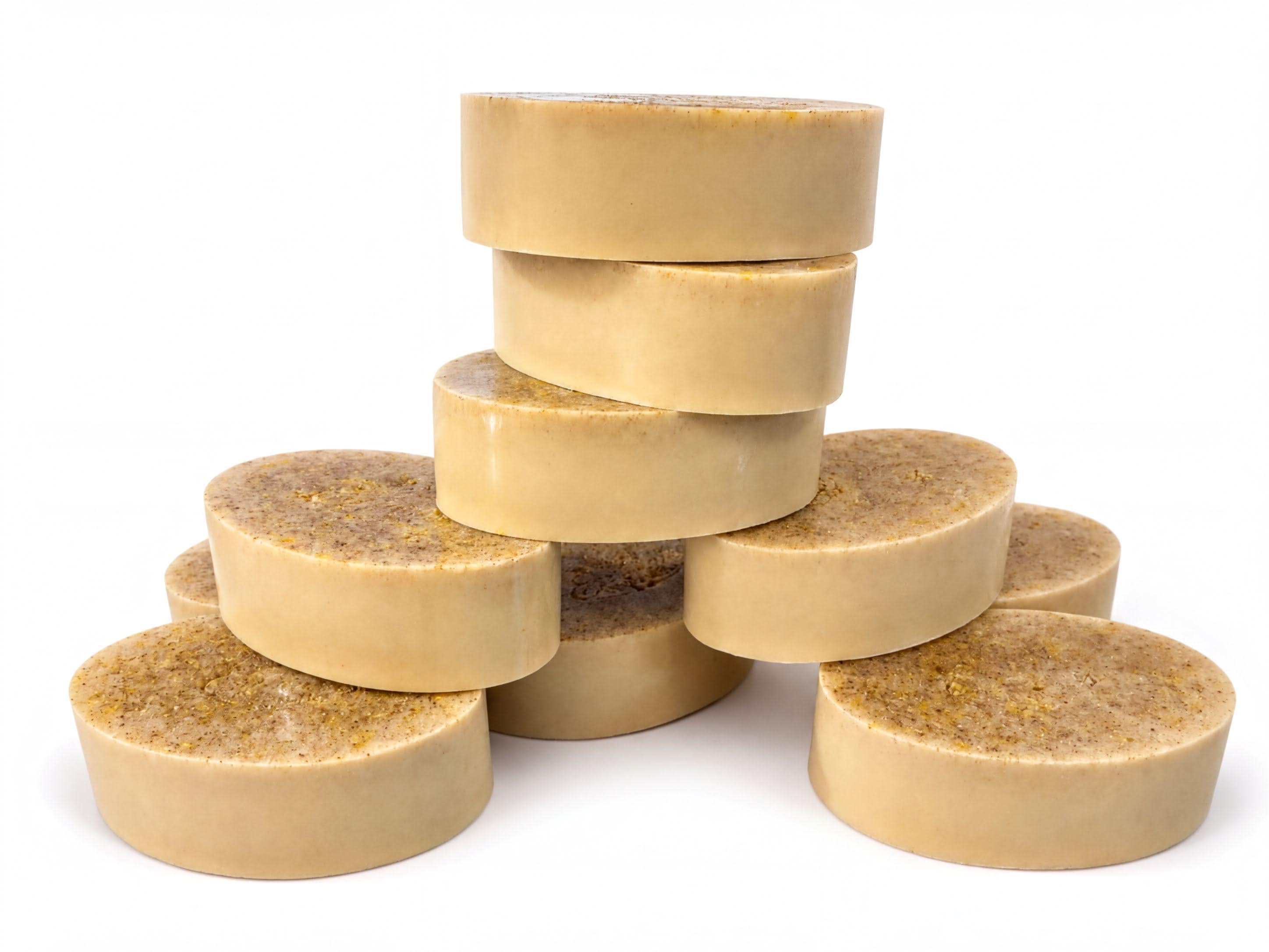 A stack of round, beige-colored soap bars or bars of soap is arranged in a pyramid-like structure against a white background.